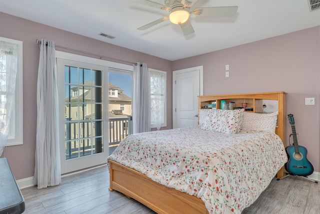 bedroom featuring baseboards, wood finished floors, visible vents, and access to exterior