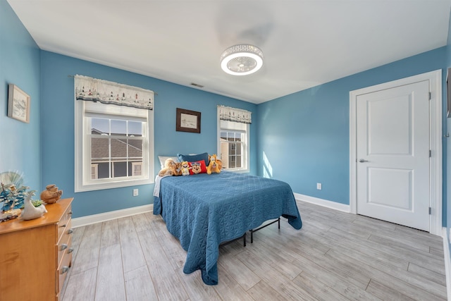 bedroom with baseboards, a ceiling fan, light wood finished floors, and visible vents