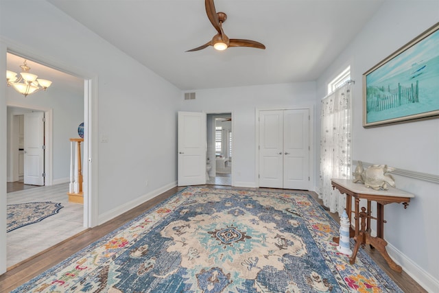 entryway with ceiling fan with notable chandelier, baseboards, wood finished floors, and visible vents