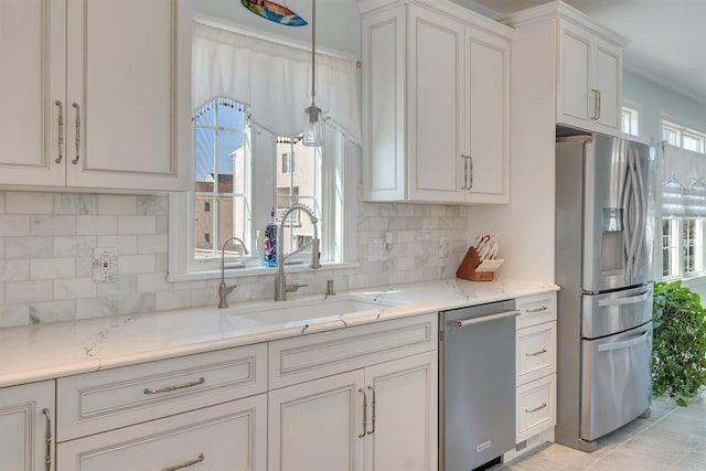 kitchen featuring decorative backsplash, a wealth of natural light, stainless steel appliances, and a sink