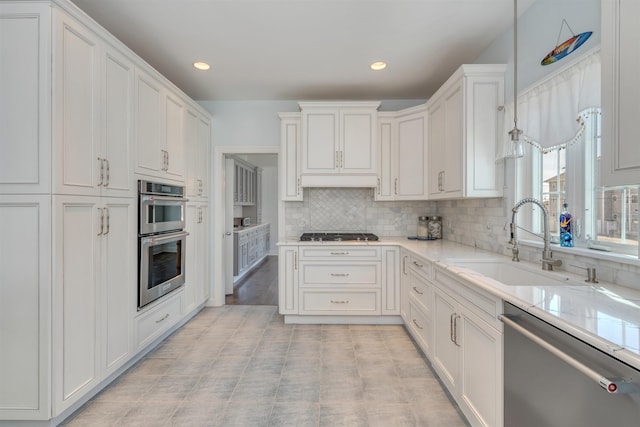 kitchen featuring a sink, stainless steel appliances, white cabinets, backsplash, and recessed lighting