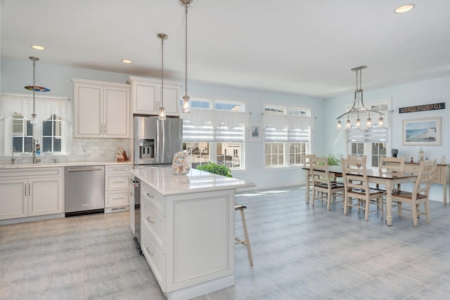 kitchen featuring light countertops, decorative light fixtures, stainless steel appliances, and a sink