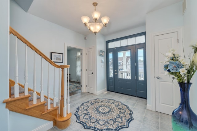 foyer entrance featuring baseboards, a notable chandelier, stairs, and light tile patterned flooring