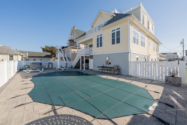 rear view of house featuring stairs, a fenced in pool, a patio, and a fenced backyard