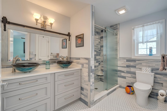 bathroom featuring a shower stall, tile patterned floors, vanity, tile walls, and toilet