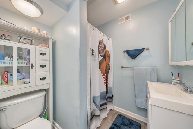 bathroom featuring toilet, baseboards, visible vents, wood finished floors, and vanity