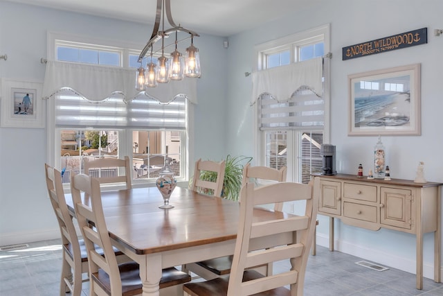 dining room featuring baseboards, visible vents, and a notable chandelier
