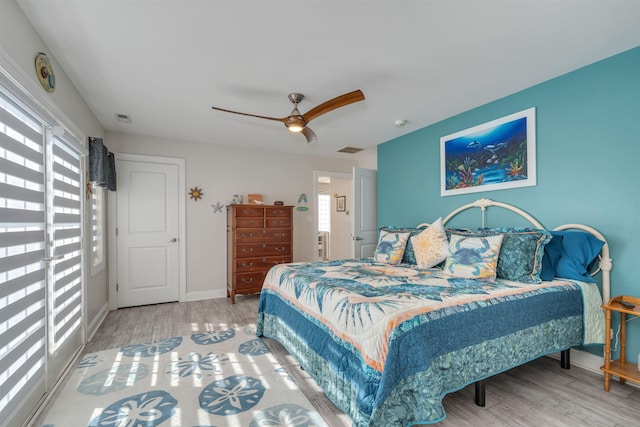 bedroom with wood finished floors, visible vents, baseboards, and ceiling fan