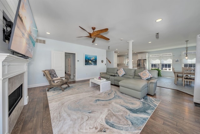 living room with baseboards, visible vents, a ceiling fan, a fireplace, and wood-type flooring