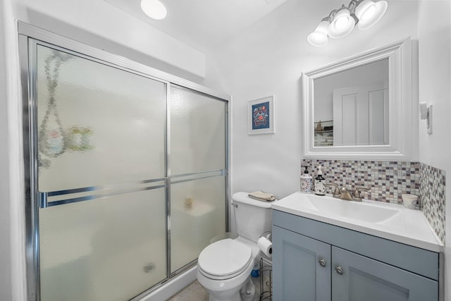 bathroom featuring toilet, a shower stall, backsplash, and vanity