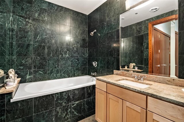 bathroom with tiled shower / bath combo, tile walls, and vanity