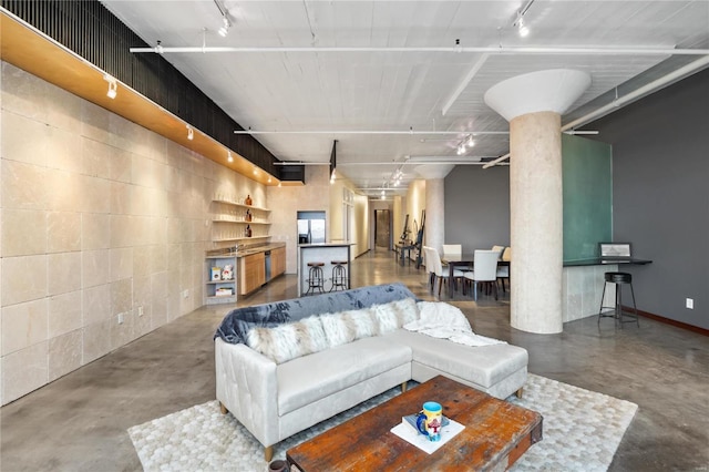 living room with decorative columns and concrete flooring