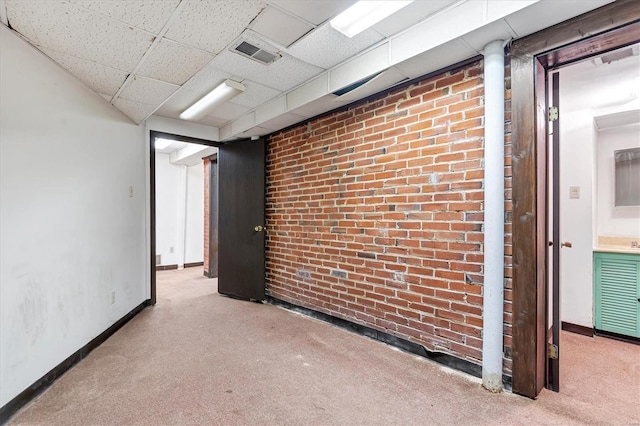 spare room with brick wall, light carpet, and a paneled ceiling