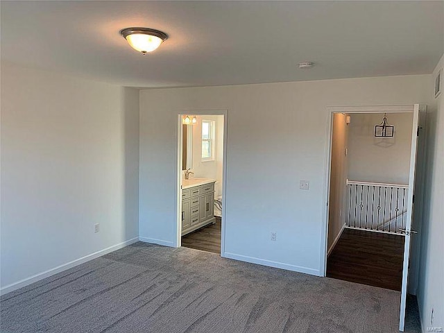 unfurnished bedroom with dark colored carpet and ensuite bathroom