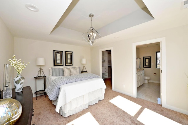 bedroom featuring an inviting chandelier, light carpet, ensuite bath, and a raised ceiling