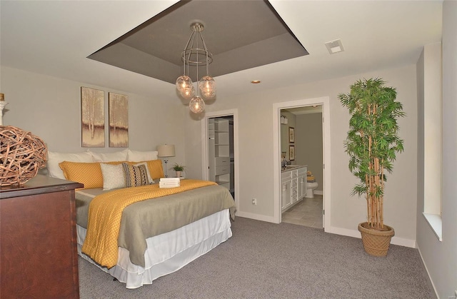 bedroom featuring a tray ceiling, ensuite bathroom, and carpet
