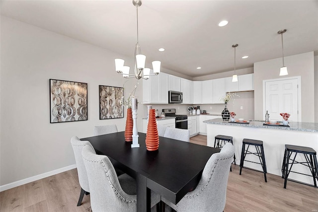 dining room with light hardwood / wood-style floors, sink, and an inviting chandelier