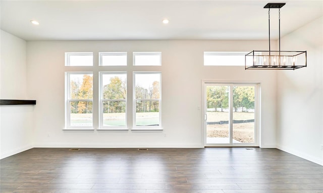 empty room featuring a notable chandelier and dark wood-type flooring