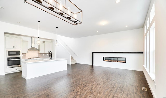 unfurnished living room with plenty of natural light, dark wood-type flooring, and sink