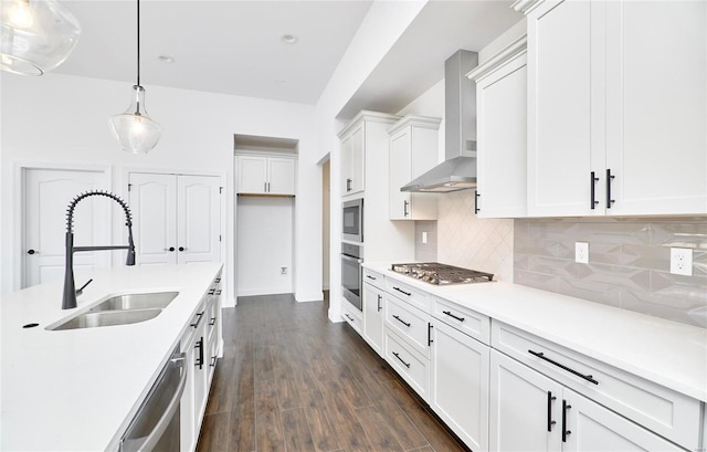 kitchen with appliances with stainless steel finishes, pendant lighting, tasteful backsplash, wall chimney range hood, and dark wood-type flooring