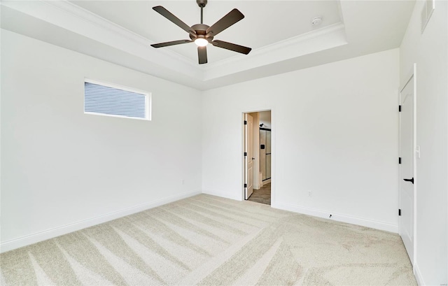 carpeted spare room with a raised ceiling, ornamental molding, and ceiling fan