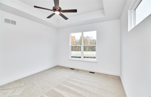 carpeted empty room with a tray ceiling, ceiling fan, and crown molding