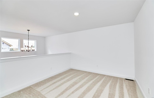 carpeted empty room with a chandelier