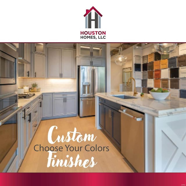 kitchen with stainless steel appliances, gray cabinetry, light hardwood / wood-style flooring, light stone countertops, and sink