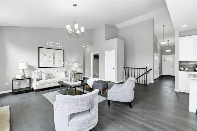 living room with dark hardwood / wood-style flooring, high vaulted ceiling, and an inviting chandelier