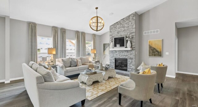 living room with a stone fireplace, a notable chandelier, high vaulted ceiling, and dark hardwood / wood-style flooring