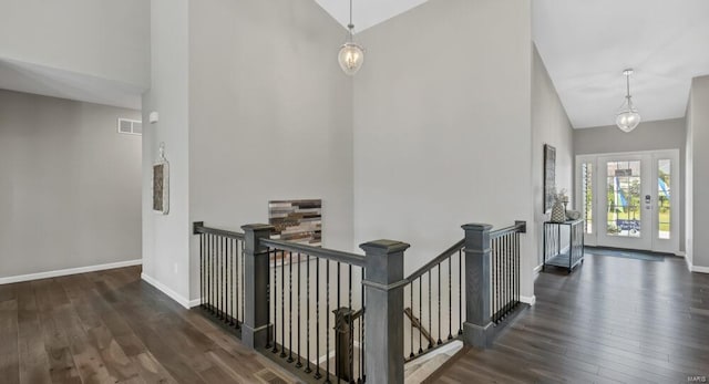 corridor with high vaulted ceiling, an inviting chandelier, and dark hardwood / wood-style floors