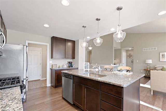 kitchen featuring sink, hanging light fixtures, dishwasher, light stone countertops, and light wood-type flooring