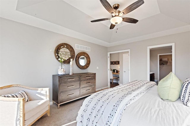 carpeted bedroom with a raised ceiling and ceiling fan