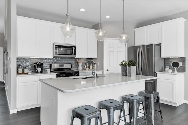 kitchen with backsplash, dark hardwood / wood-style floors, hanging light fixtures, and appliances with stainless steel finishes