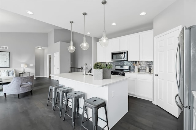 kitchen featuring dark hardwood / wood-style floors, pendant lighting, white cabinets, stainless steel appliances, and tasteful backsplash