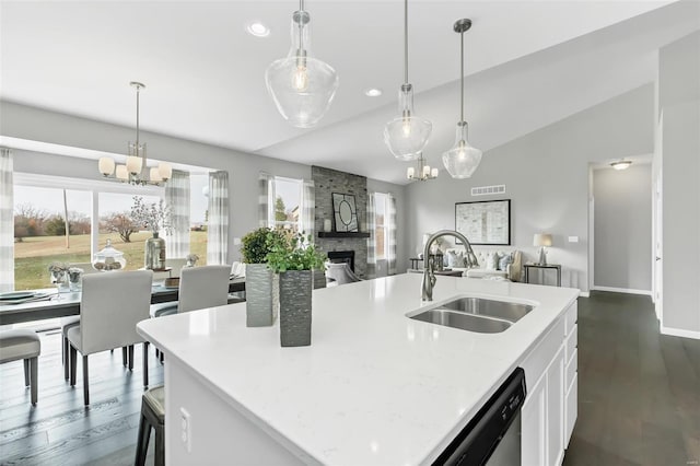 kitchen featuring dark wood-type flooring, a fireplace, sink, white cabinets, and pendant lighting