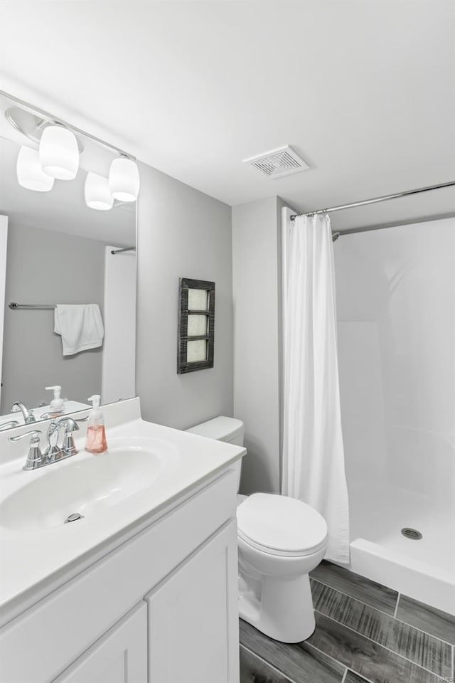 bathroom featuring vanity, toilet, and walk in shower