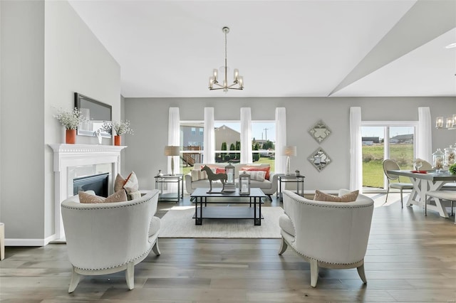 living room with a notable chandelier, vaulted ceiling, and wood-type flooring