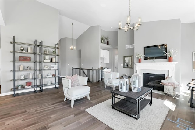 living room with an inviting chandelier, high vaulted ceiling, and dark wood-type flooring