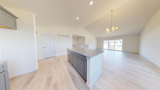 kitchen featuring light hardwood / wood-style flooring, light stone counters, lofted ceiling, pendant lighting, and gray cabinets