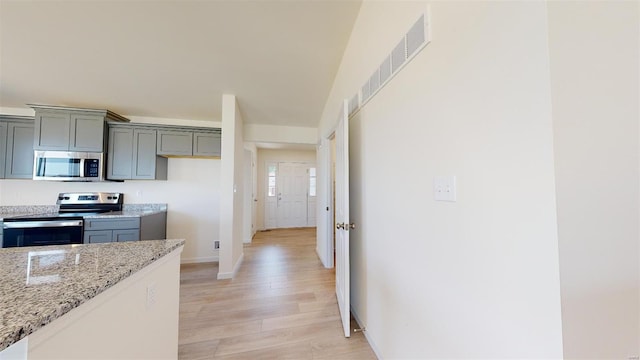 kitchen featuring light hardwood / wood-style flooring, gray cabinets, stainless steel appliances, and light stone countertops