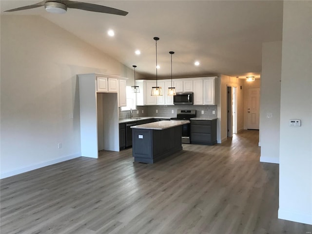 kitchen featuring white cabinets, appliances with stainless steel finishes, a center island, and dark hardwood / wood-style flooring