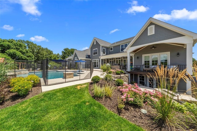 rear view of house featuring ceiling fan, a yard, a fenced in pool, and a patio