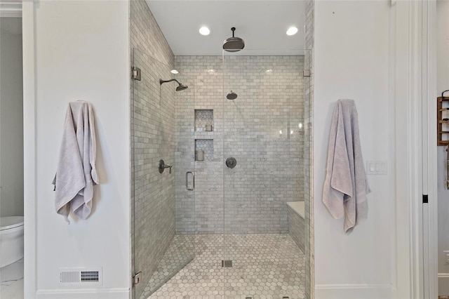 bathroom with a shower with shower door and toilet