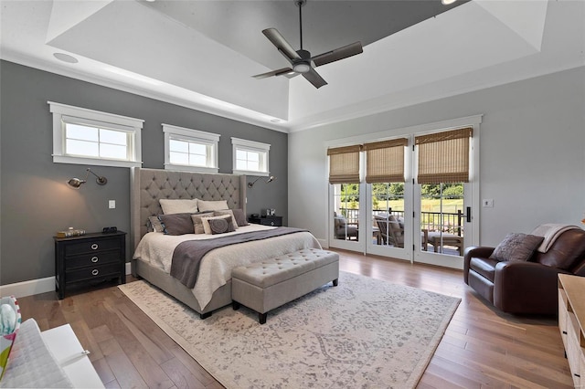 bedroom featuring multiple windows, dark wood-type flooring, ceiling fan, and a raised ceiling