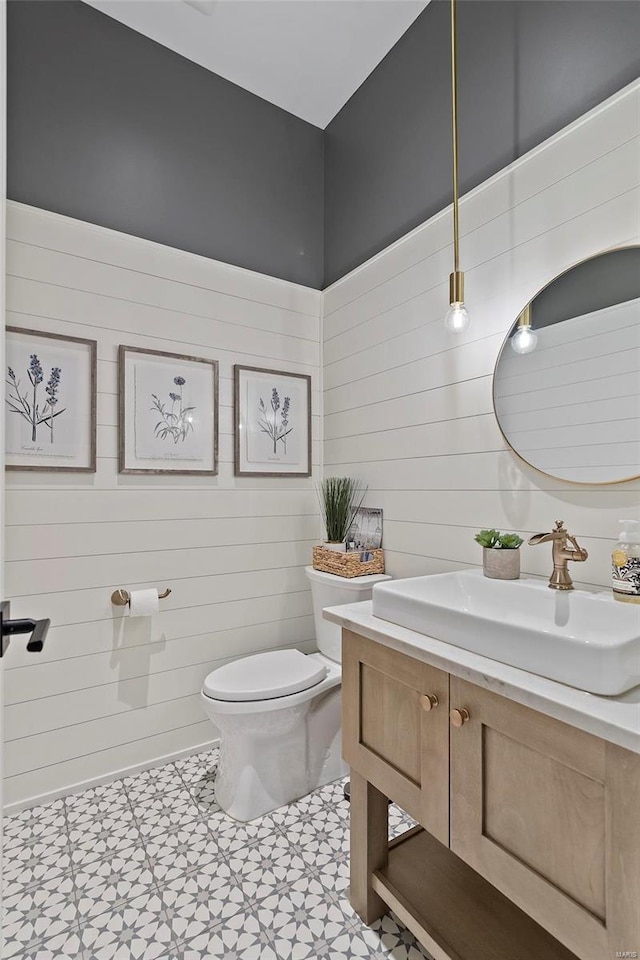 bathroom with vanity, tile floors, wood walls, and toilet