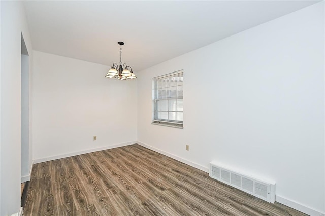 empty room featuring a chandelier and hardwood / wood-style floors