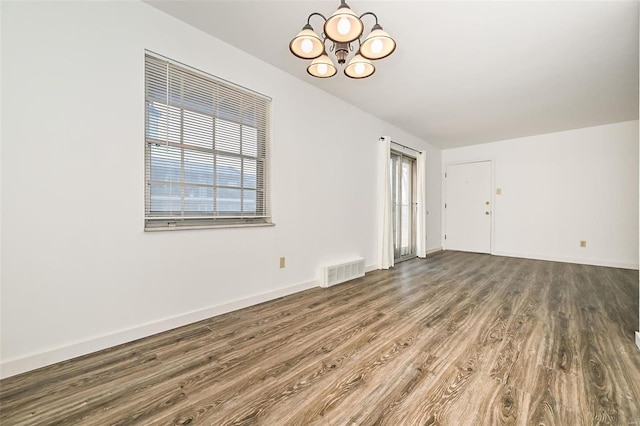 unfurnished room with hardwood / wood-style floors and a notable chandelier