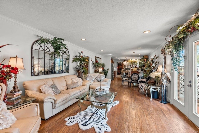 living room with a notable chandelier, ornamental molding, light hardwood / wood-style flooring, and a textured ceiling