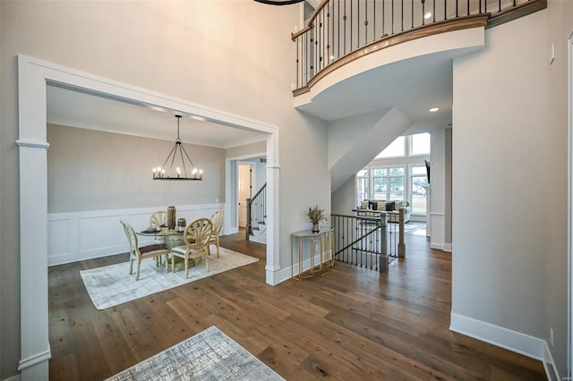 dining room featuring a towering ceiling, a chandelier, ornamental molding, and dark hardwood / wood-style floors